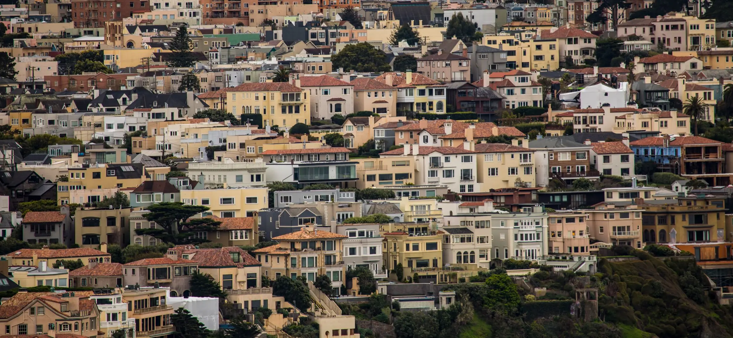Dense hillside of pastel San Francisco homes in warm light