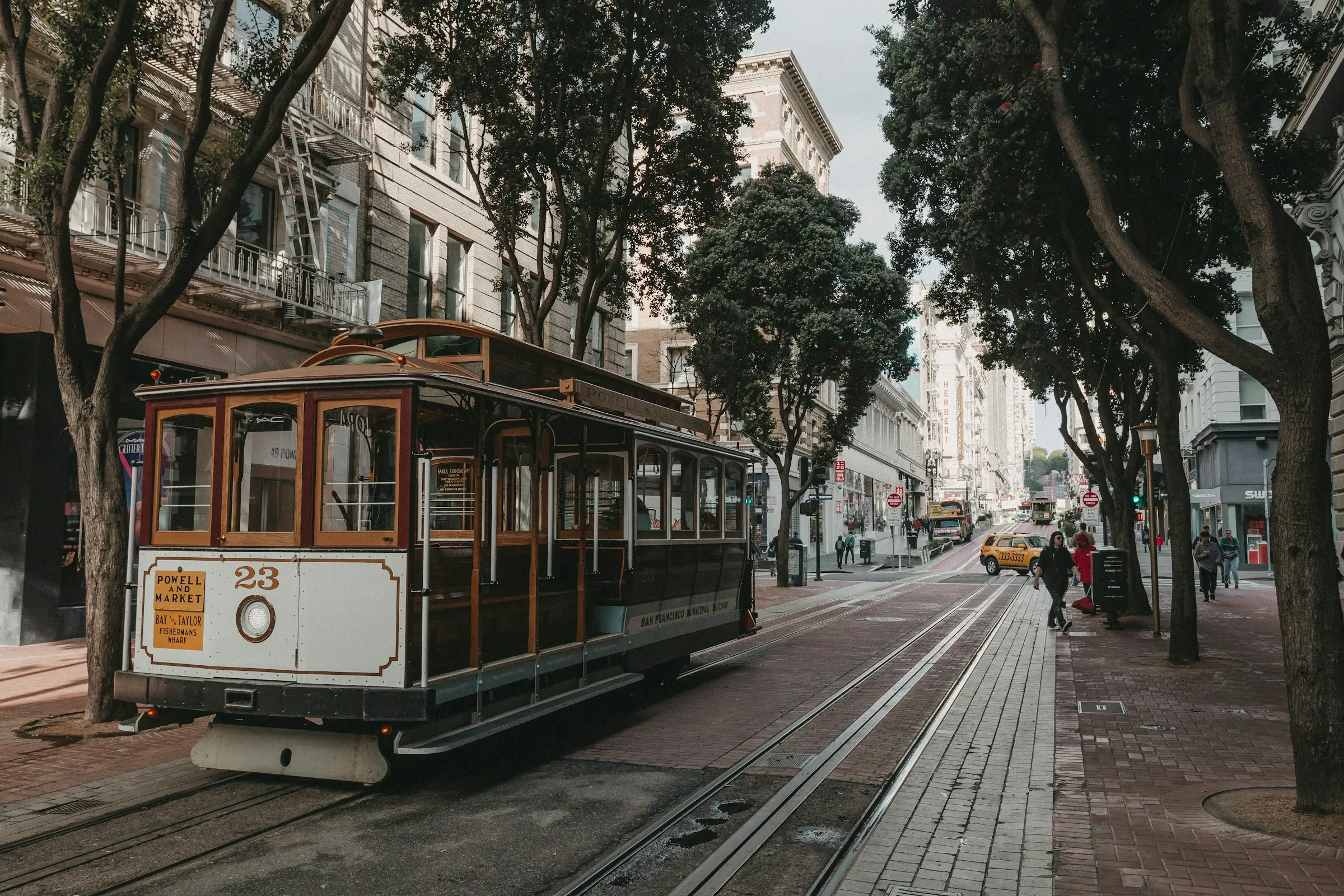 A wooden cable car on a quiet street shaded by trees
