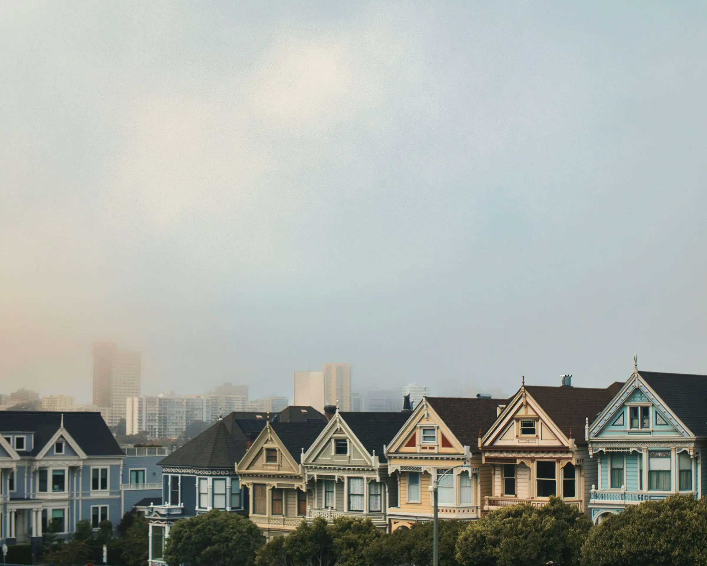 The Painted Ladies under a bank of fog, with downtown towers fading into the mist
